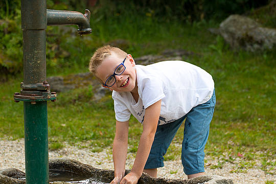 Junge spielt am Pump-Brunnen