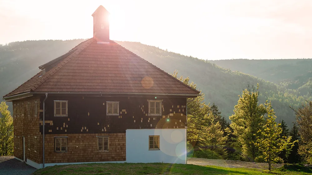 Außenansicht des Paul-Friedl-Hauses im Freilichtmuseuem Finsterau bei Sonnenuntergang Ein altes Bauernhaus im Gegenlicht