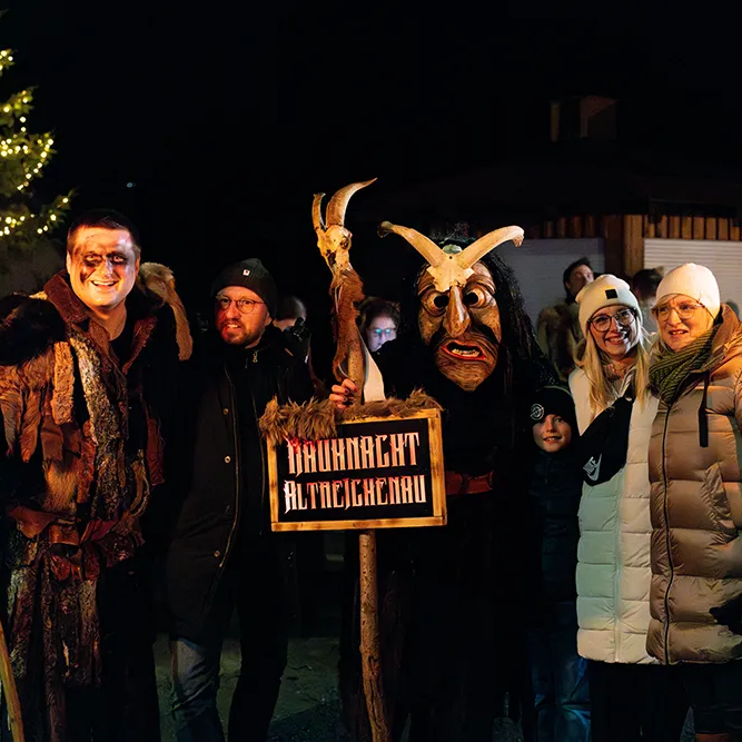 Festliche Rauhnacht mit traditionellen Masken und Fackeln Die Teilnehmer der traditionellen Rauhnachtsfeier in Altreichenau stehen zusammen, einige tragen typische Lousnachtsmasken und Kostüme.
