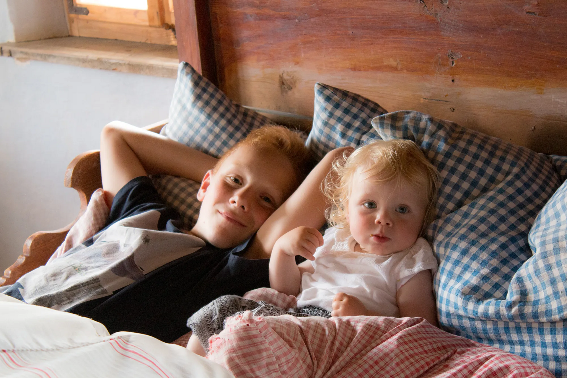 Ein kleiner Junge und ein kleines Mädchen liegen in einem hölzernen Bett Kinder kuscheln im Bett