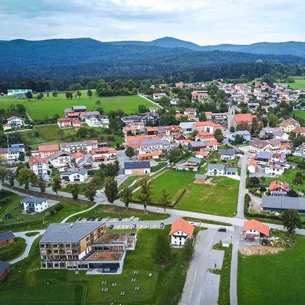 Friedliches Neuschönau zum Entschleunigen mit Blick auf den Hausberg Lusen Blick aus der Luft auf Neuschönau, Lusen und Baumwipfelpfad im Hintergrund