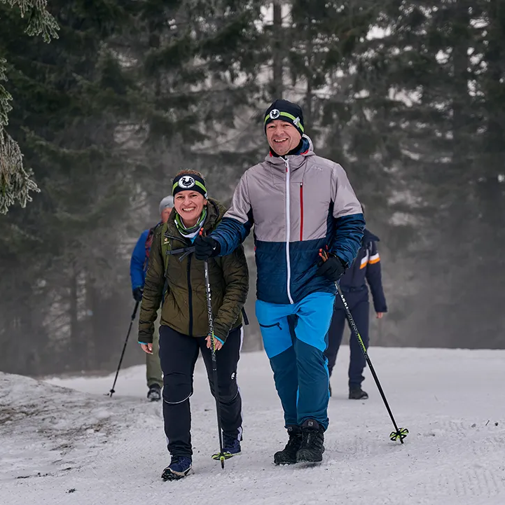 Freunde genießen eine Winterwanderung Ein fröhliches Paar wandert auf einem verschneiten Weg durch die Wälder der Ferienregion Nationalpark Bayerischer Wald