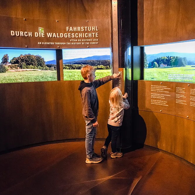 Ein Junge und ein Mädchen schauen eine Ausstellung in einem Museum an mit interaktiven Spielelementen. Kinder im Museum