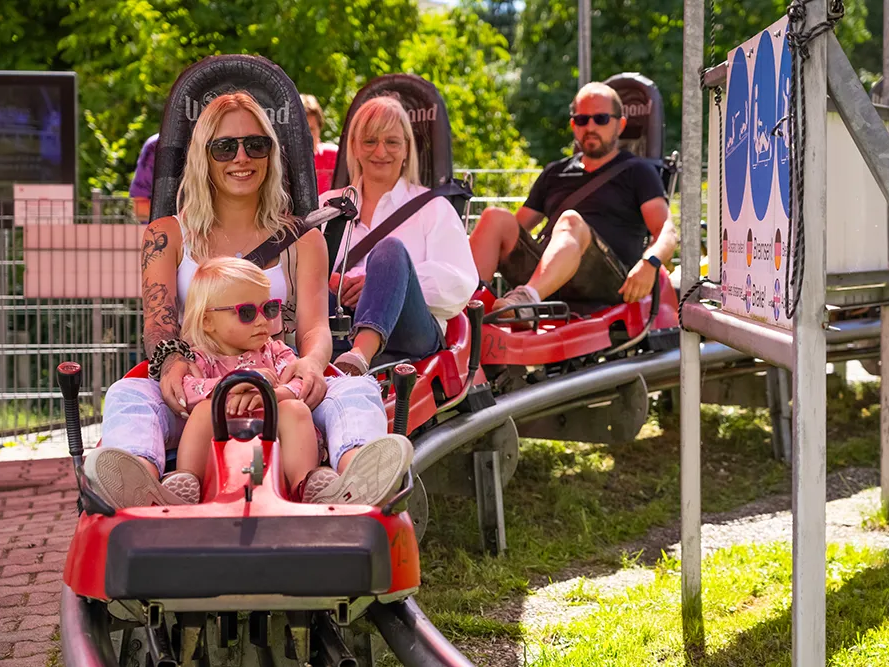 Spaßige Rodelpartie mit Kind an einem sonnigen Tag im Bärenbob Bärenbob Grafenau