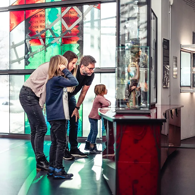 Familie betrachtet eine Vitrine mit alten Gläsern im Museum in Frauenau Familie im Glasmuseum