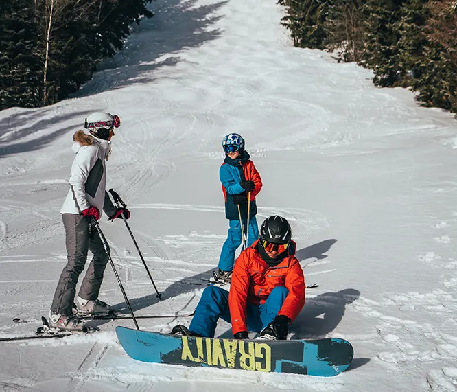 Winterabenteuer: Skifahrer und ein Snowboarder genießen die Pisten im Wald Ski- und Snowboardfahrer bereiten sich auf die Abfahrt am Spicak in Tschechien vor