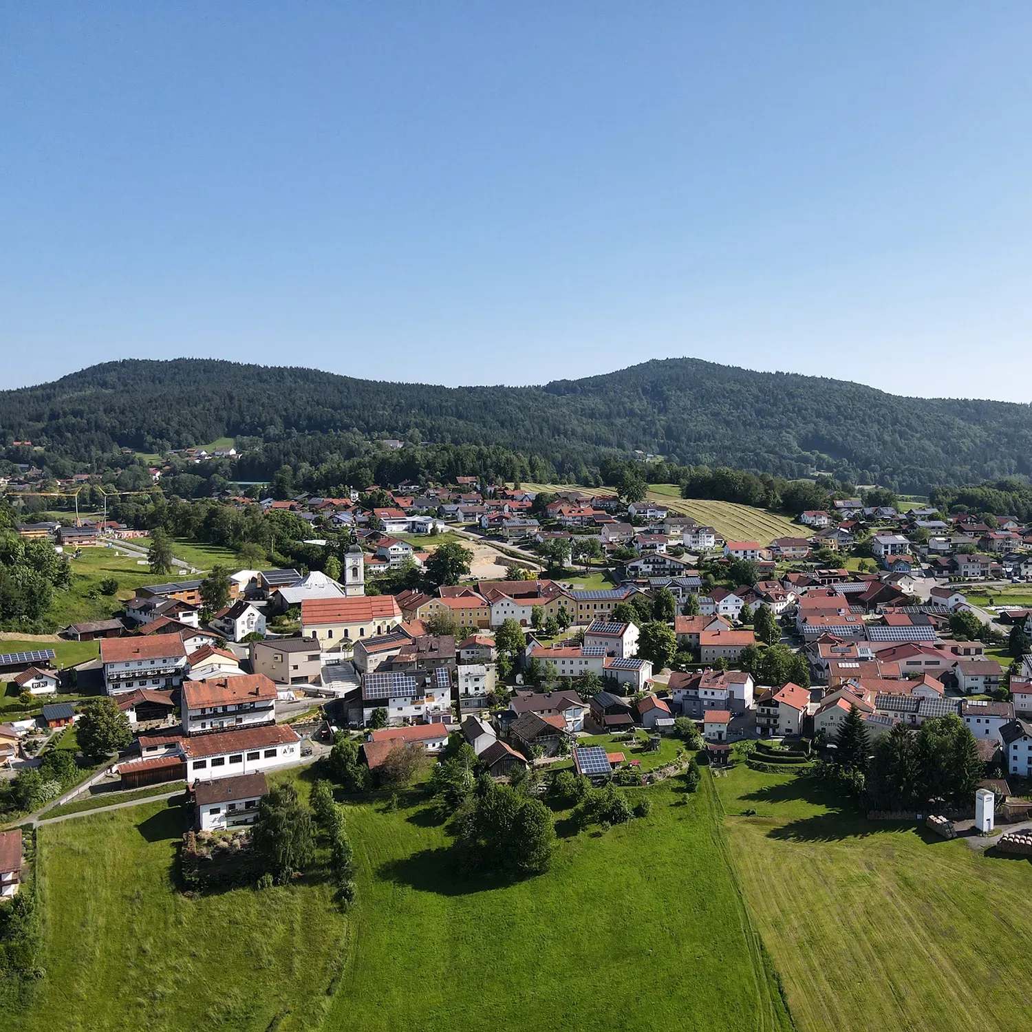Gemeinde Kirchdorf mit grünem Wald im Hintergrund und sommerlichen grünen Wiesen Sommerbild der Gemeinde Kirchdorf im Wald von der Luft aus