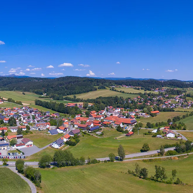 Eine weite Landschaft eröffnet sich rund um Eppenschlag, einem kleinen Dorf unter strahlend blauem Himmel, der die Idylle unterstreicht.