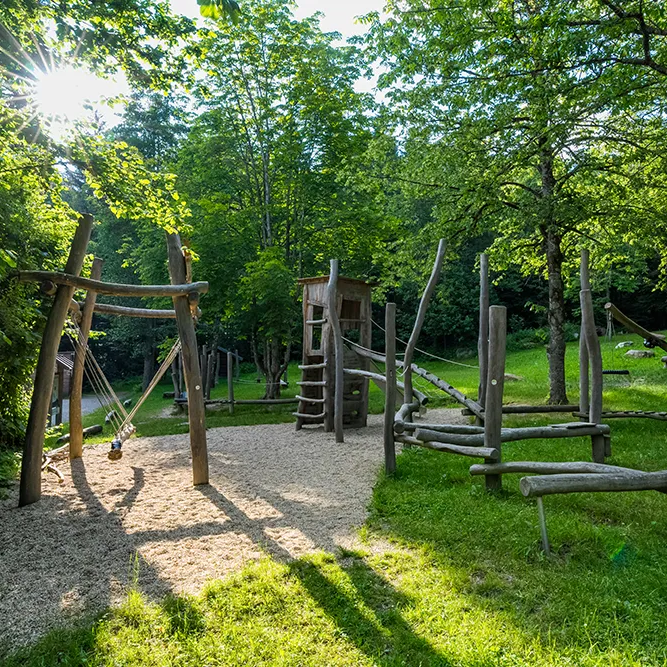 Sonnenlicht erleuchtet den Fuchsspielplatz in Kirchdorf inmitten von grünen Bäumen Fuchsspielplatz