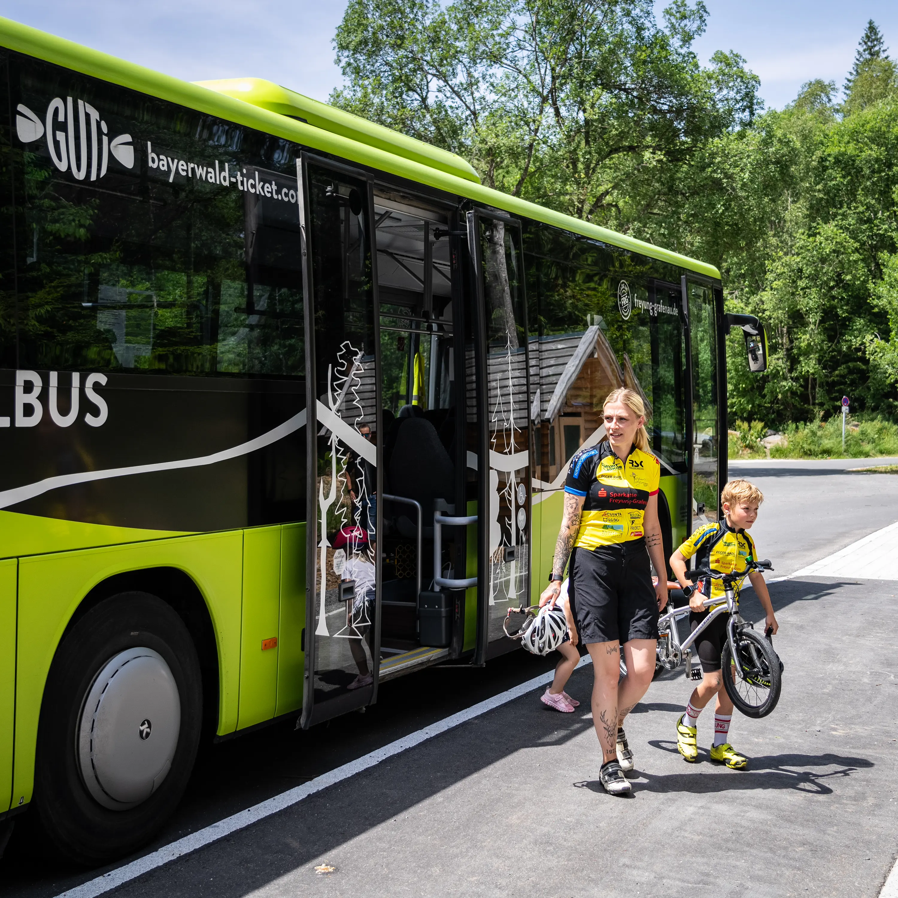 Eine Frau steigt mit ihrem Kind und einem Fahrrad aus dem Igelbus aus