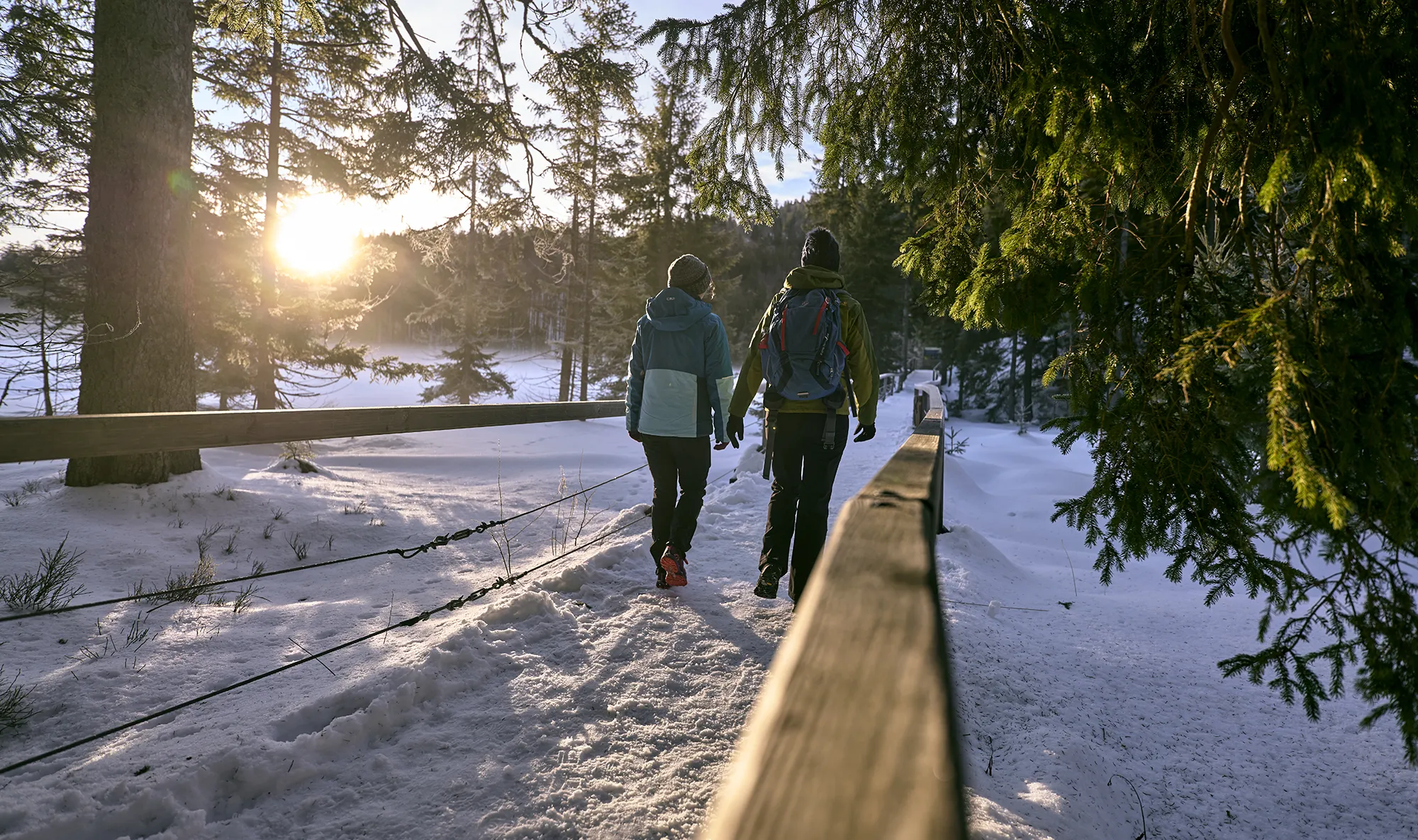 Zwei Frauen wandern auf verschneitem Steig um den Arbersee